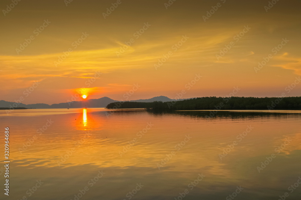 Sea view evening of sundown with yellow sun light and cloudy sky background, sunset at Kuraburi Pier, Phang Nga, southern of Thailand.