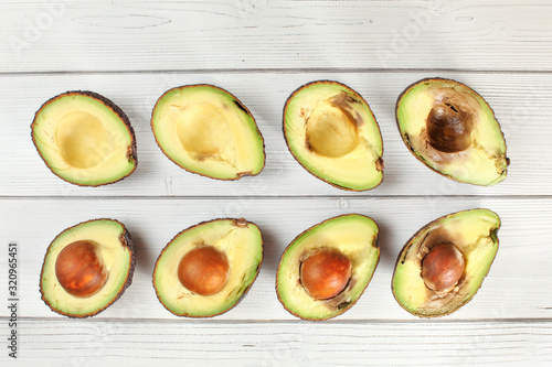 Avocado halves arranged from ripe to over ripen on white boards desk, view from above