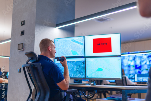 Фотография Male computer operator monitoring from a security ( computer, logistic ) center
