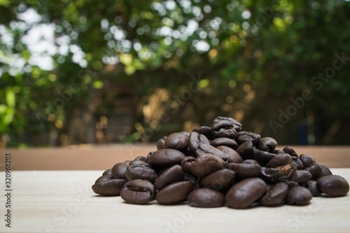 pile of coffee beans on bright wooden tray with nature background
