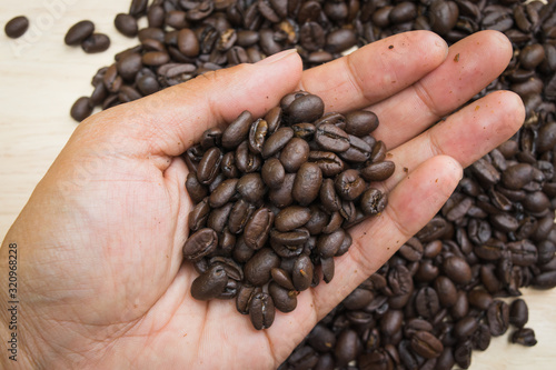men hand hold coffee beans on bright wooden background