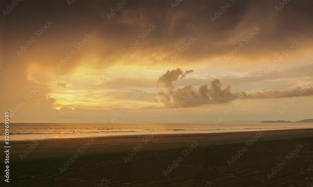 view seaside of soft raining in the sea and yellow sun light in the sky background, sunset with raining at Laem Son beach, Laem Son National Park, Ranong, southern of Thailand.