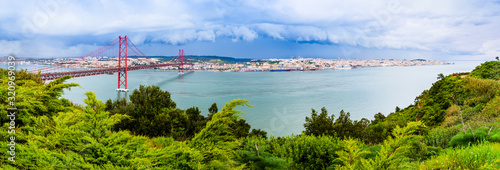 Landscape of Lisbon, Portugal skyline and the 25th of April bridge over the Tagus river estuary as seen from the hills of Almada photo
