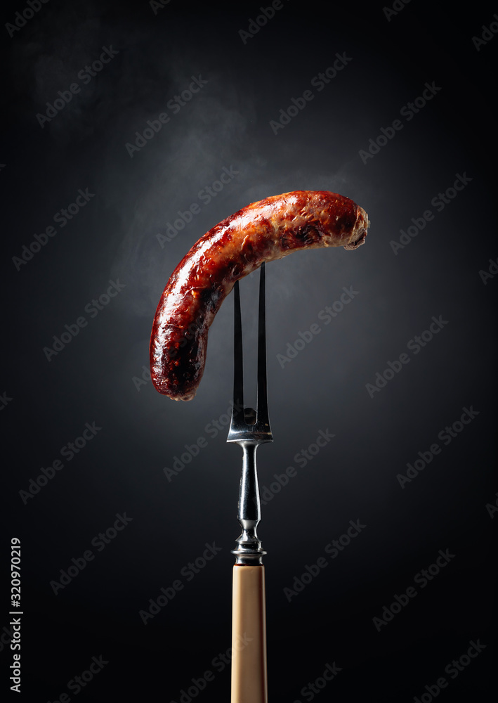 Grilled Bavarian sausage on a fork. - obrazy, fototapety, plakaty 