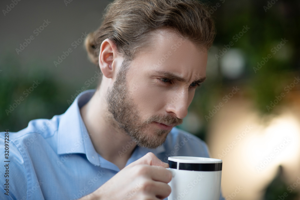 Young serious man with smart look with cup in his hand. Young serious man with smart look with cup in his hand.