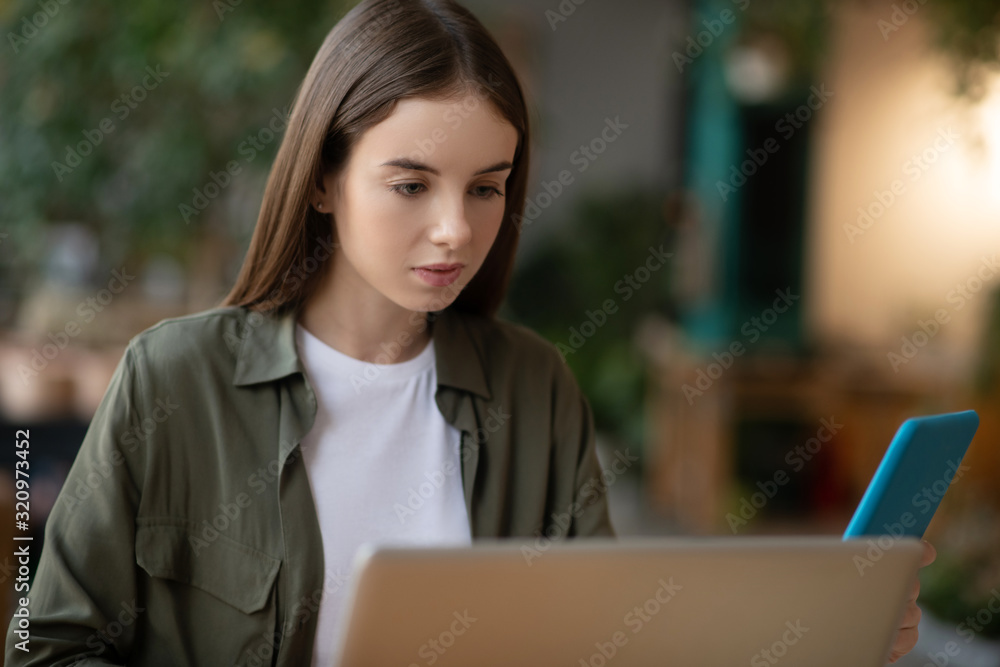 Tired girl working at a laptop, looking at a tablet. Tired girl working at a laptop, looking at a tablet.