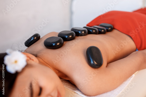 Woman lying on massage table with stones on her back at spa