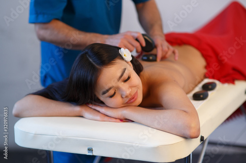 Woman lying on massage table with stones on her back at spa