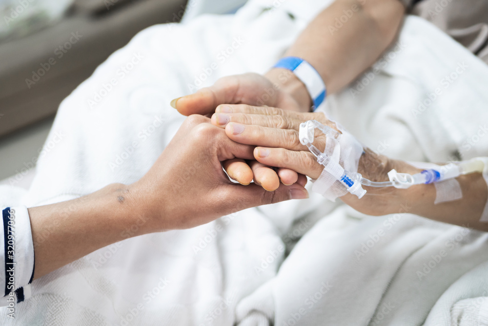 Elderly woman patient hold hand of daughter while lying on hospital bed private room. Elderly woman patient hold hand of daughter while lying on hospital bed private room.