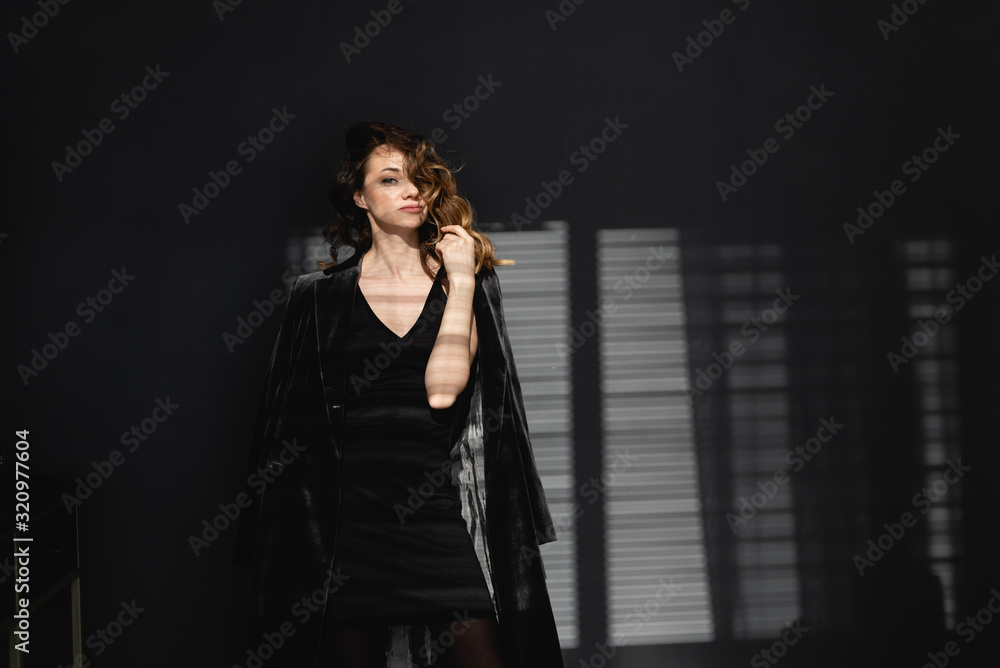 stylish young girl with curly red hair on a dark background. Confident stylish and bold.