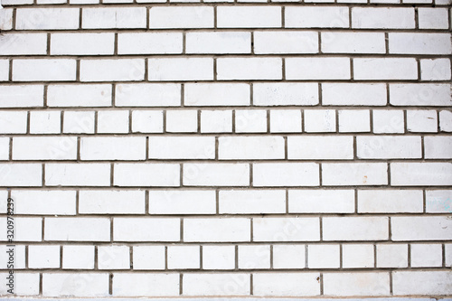 Old white brickwall textured background. Dirty and grungy texture of brick masonry. Outdoor urban surface. Façade of a building. Bricks with cement (concrete) in grunge solid laying. Stonework pattern