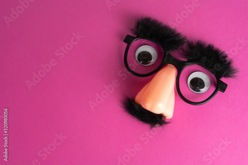 Funny face mask with big eyes and pink background with lot of copy space