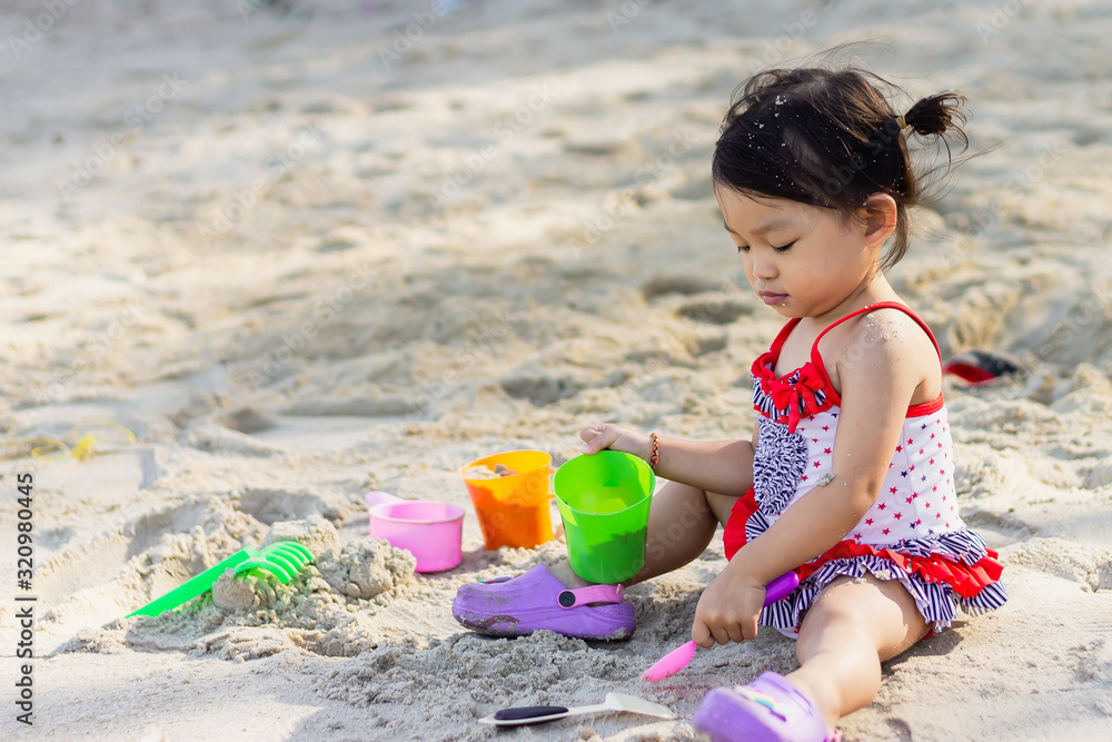 Portrait image of baby 1-2 years old. Happy Asian child girl playing sand on the beach at the sea. In the summer season. Portrait image of baby 1-2 years old. Happy Asian child girl playing sand on the beach at the sea. In the summer season.