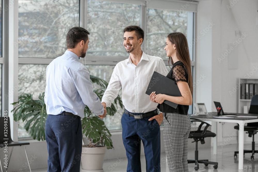Bank manager shaking hands with couple in office Bank manager shaking hands with couple in office