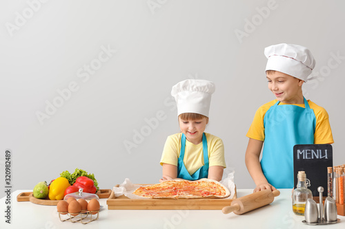 Cute little chefs cooking on light background