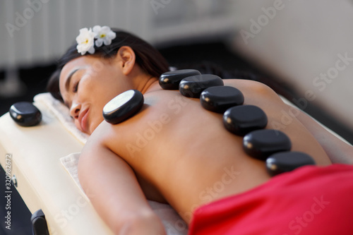 Woman lying on massage table with stones on her back at spa