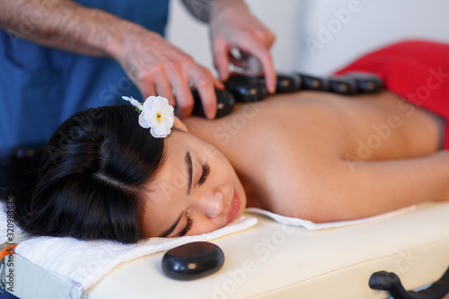 Young Asian woman enjoying the therapeutic effects of a traditional hot stone massage at luxury spa and wellness center