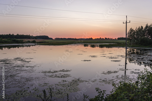 Sunset over pond next to bike path between Polczyn Zdroj town and Zlocieniec town located in West Pomerania region of Poland photo