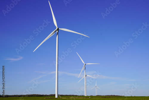 Wind turbines and agricultural fields on summer day blue sky