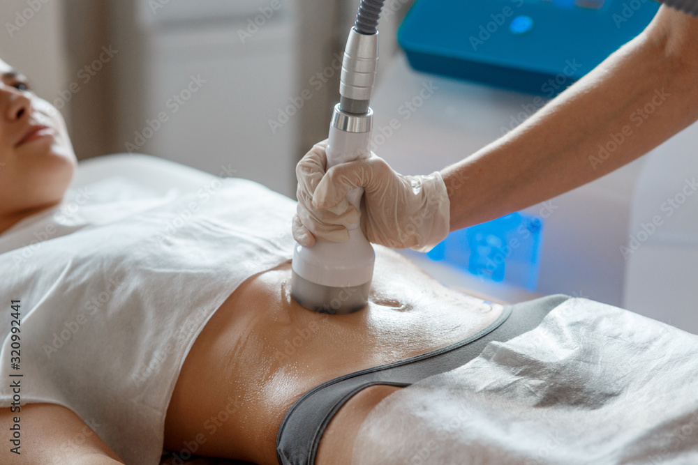 © Ilnur - Hardware cosmetology. Body care. Spa treatment. Ultrasound cavitation body contouring treatment. Woman getting anti-cellulite and anti-fat therapy in beauty salon.