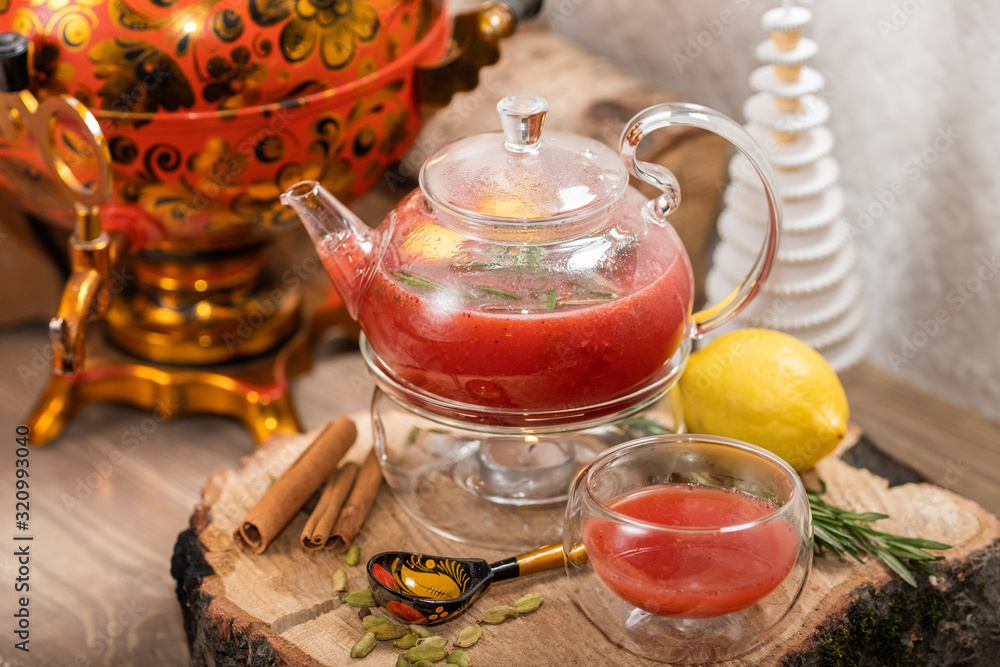 Hot fruit red berry tea with steam in the teapot with mint, berries, lemon slices on wooden background. Food and drink. New year holidays, christmas xmas dinner concept Hot fruit red berry tea with steam in the teapot with mint, berries, lemon slices on wooden background. Food and drink. New year holidays, christmas xmas dinner concept