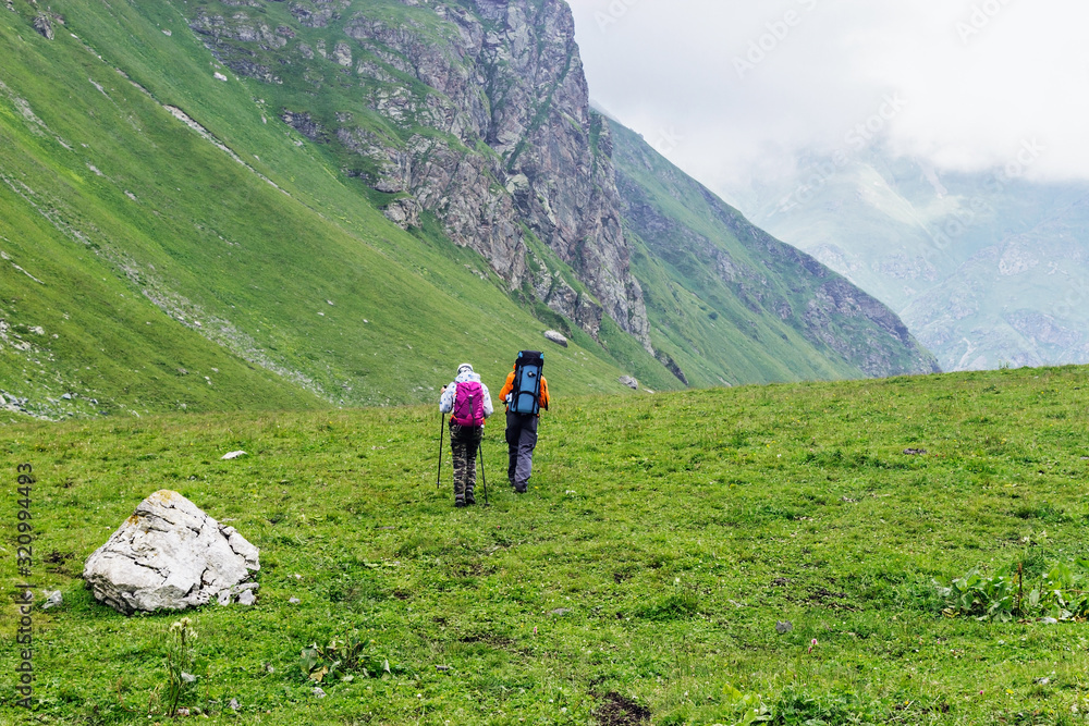 tourists with backpacks travel in the caucasus mountains