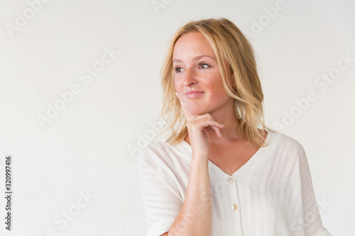 Smiling dreamy woman looking aside. Portrait of pensive young woman holding hand on chin and looking away isolated on white background. Dream concept