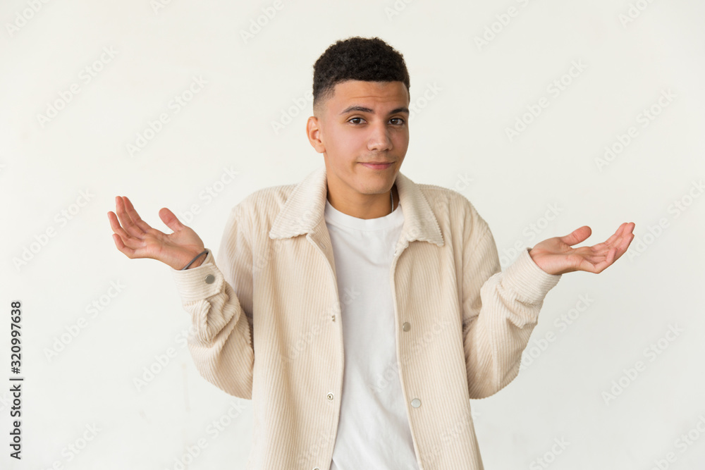 Young man shrugging and looking at camera. Portrait of doubtful young man gesturing with hands and looking at camera isolated on white background. Doubt concept Young man shrugging and looking at camera. Portrait of doubtful young man gesturing with hands and looking at camera isolated on white background. Doubt concept