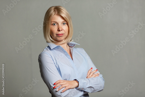 Young smiling woman in a blue shirt and trousers. Business success. Gray background.