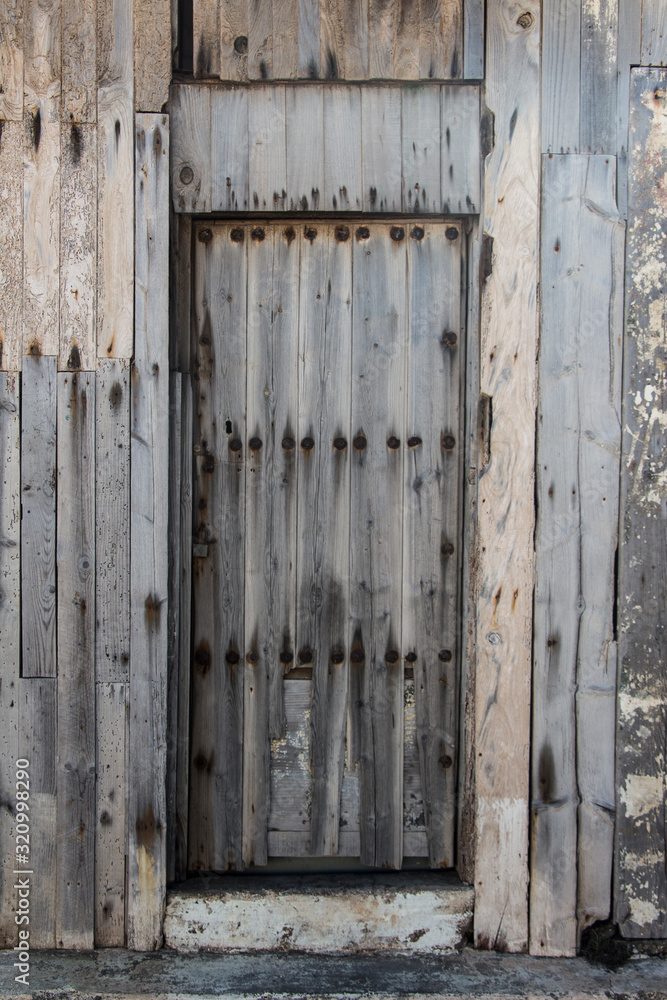 old wooden door with rusty tacks of a warehouse or a barn, old gate made of wood, light wooden planks on a rural barn gate, vintage old warehouse wooden gate, wooden texture or background old wooden door with rusty tacks of a warehouse or a barn, old gate made of wood, light wooden planks on a rural barn gate, vintage old warehouse wooden gate, wooden texture or background