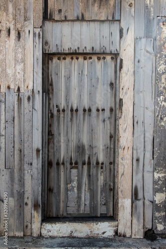 old wooden door with rusty tacks of a warehouse or a barn, old gate made of wood, light wooden planks on a rural barn gate, vintage old warehouse wooden gate, wooden texture or background
