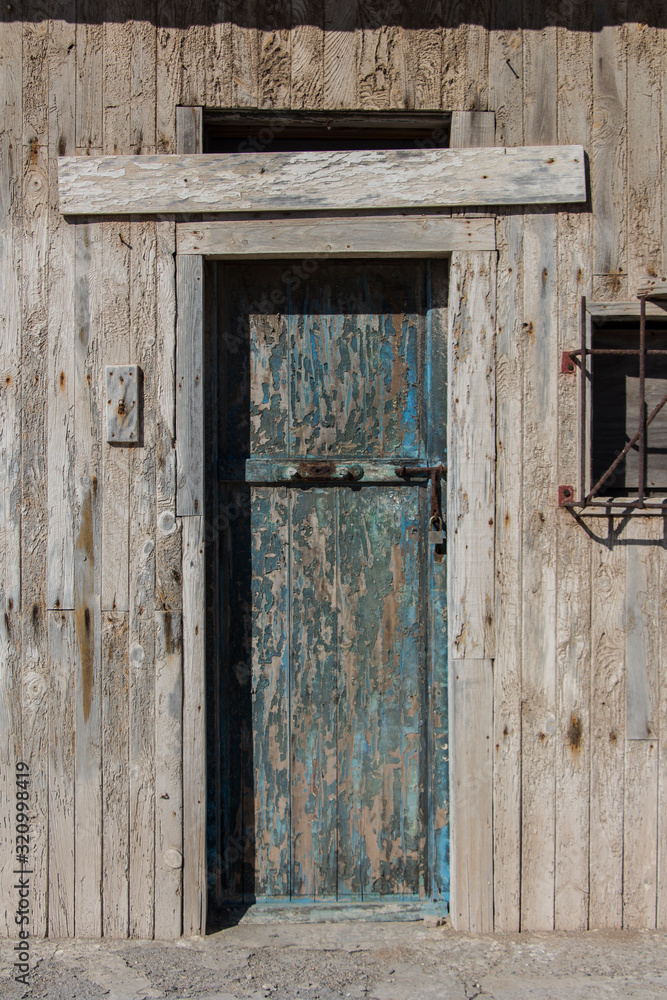 old wooden door with traces of blue paint, old wooden door of a warehouse or a barn, old gate made of wood, wooden texture or background, vintage old warehouse wooden gate