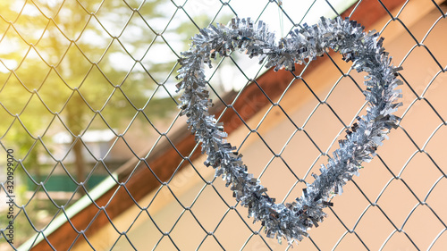 Silver heart shaped garland hanging in the window of the iron net