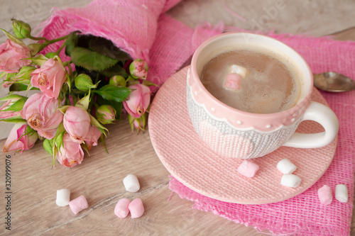 cup in pink sweater effect with heart pattern. Pink roses, cappuccino with marshmallow