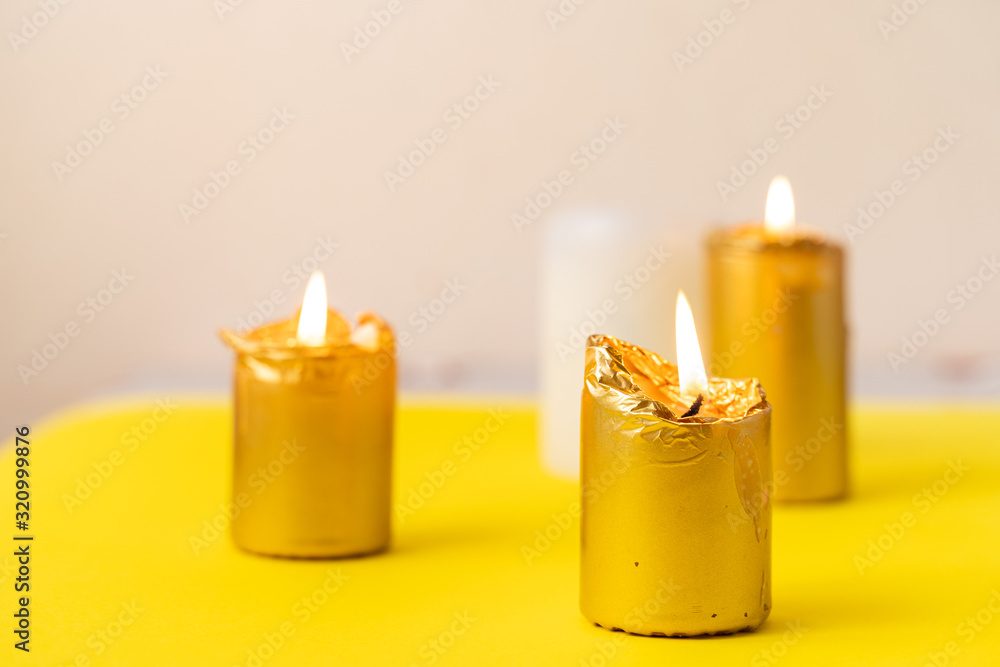 golden candles on yellow background. Wellnes, magic, relax concept. Cozy home. Copy space - obrazy, fototapety, plakaty 