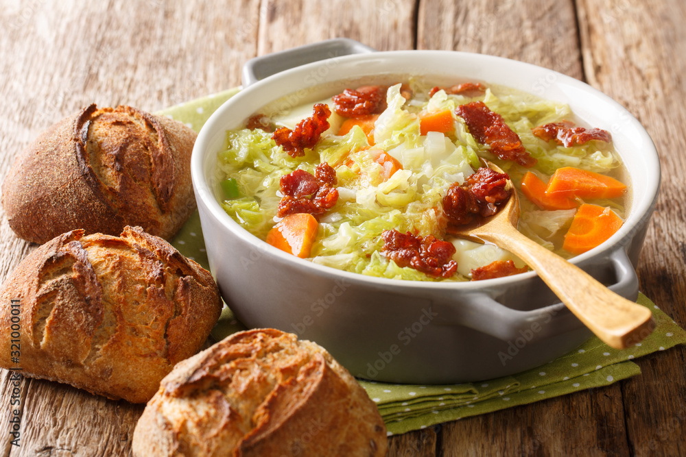 Vegetable cabbage soup with fried bacon served with bread close-up in a bowl. horizontal Vegetable cabbage soup with fried bacon served with bread close-up in a bowl. horizontal