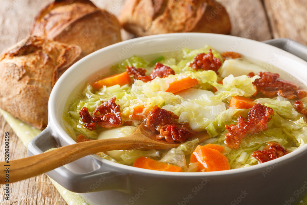 Savoy cabbage soup with potatoes and bacon close-up in a bowl on the table. horizontal