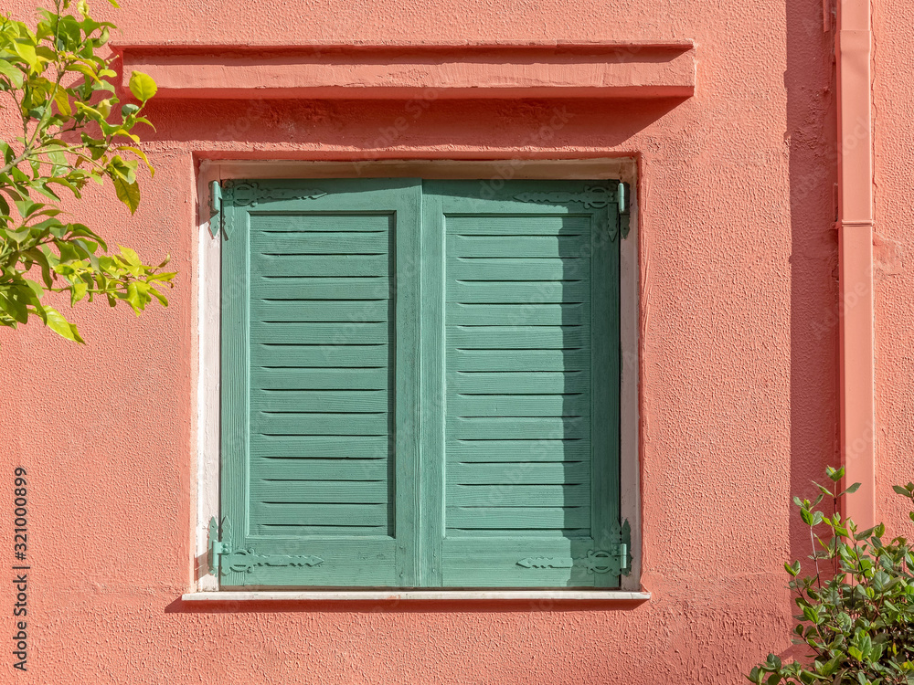 vibrant green shutters window on peach colored wall