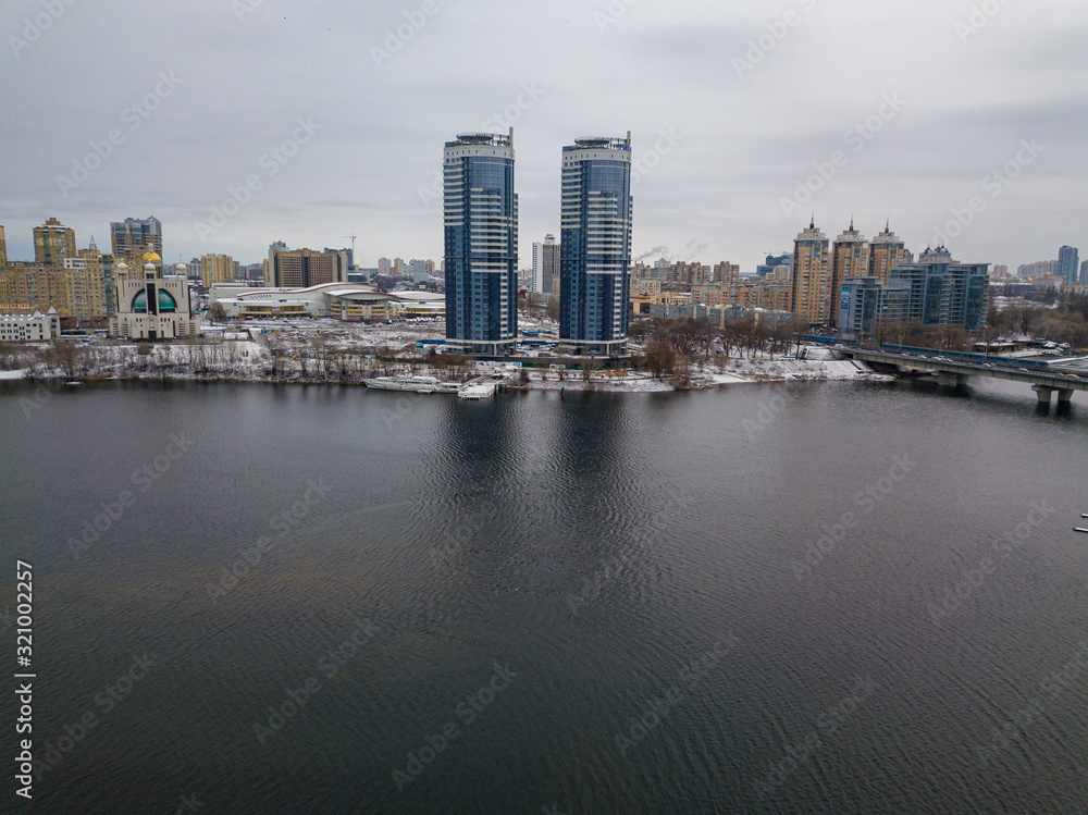 Aerial drone view. The left bank of Kiev in snowy weather against the backdrop of the river.