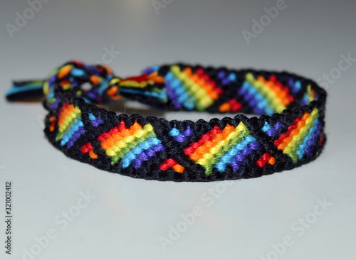 Friendship bracelet handmade of thread with pattern of the rainbow flag, known as the gay pride flag or LGBT pride flag