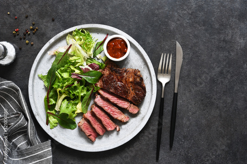 Grilled marbled beef steak with salad in a plate on the kitchen table. With copy space under the text.