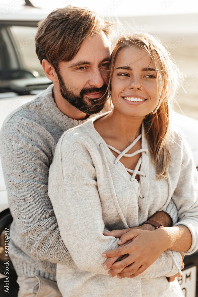© Drobot Dean - Loving couple outdoors at beach near car hugging.