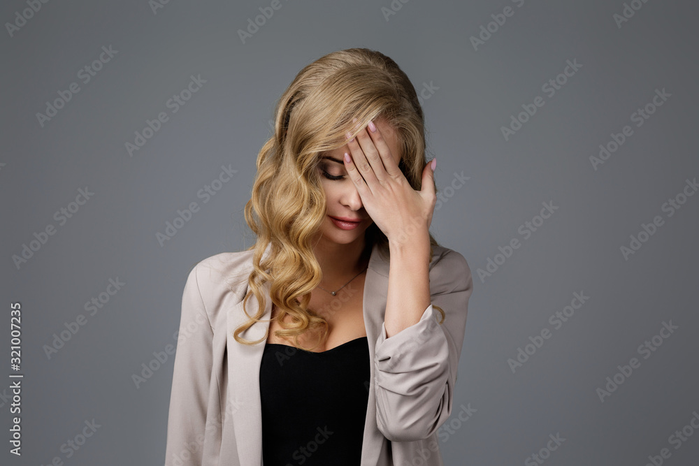 Portrait of beautiful sad woman with hand on face on gray background. young woman feeling stress and headache Portrait of beautiful sad woman with hand on face on gray background. young woman feeling stress and headache