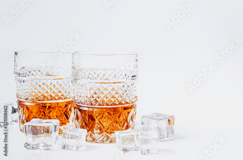 two glasses of whiskey with ice on a white background with place for text photo