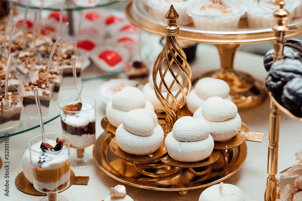Cupcakes, desserts and sweets on table party at wedding reception. Stylish candy bar. Christmas and New Year feast. Celebrations and party