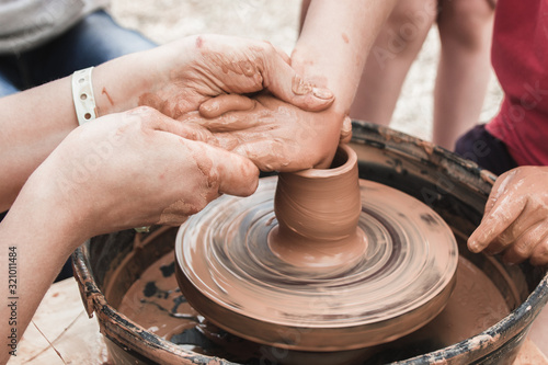 A close up view on ceramic production process on potter's wheel with children. Clay crafts with kids concept.