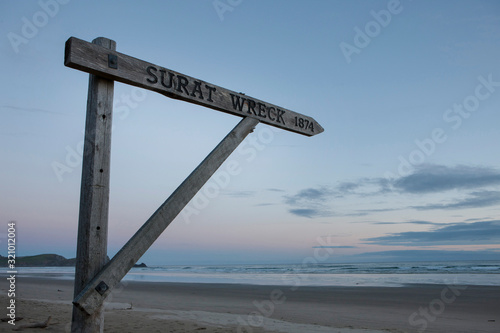 Surat Bay Catlins New Zealand. Driftwood. Wooden sign at beach says : Surat wreck 1874 sunset