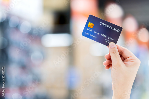 business shopping merchant ideas concept Close up of woman hand holding credit card for shopping with abstract blur mall background photo