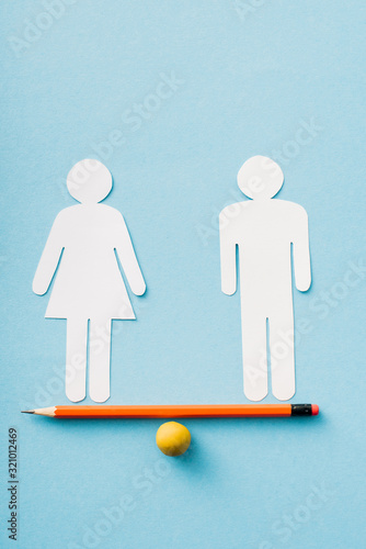 Obraz na plátně paper figures of couple as gender equality on pencil with ball isolated on blue,