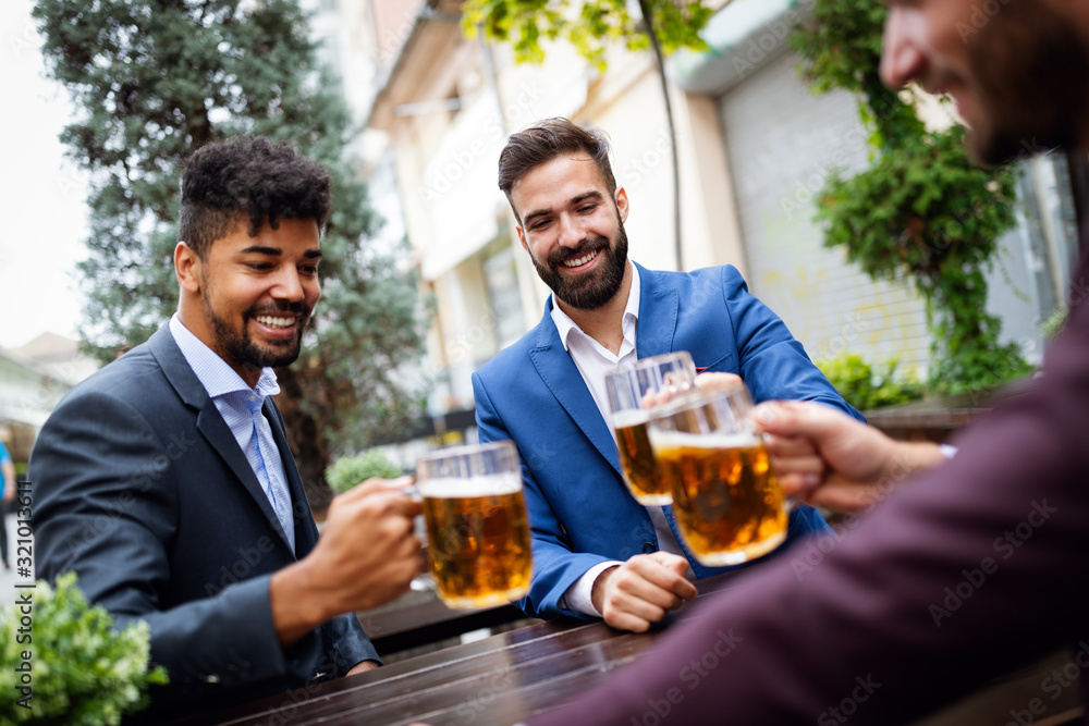 Meeting with the best friends. Happy young business men talking and drinking beer in a pub Meeting with the best friends. Happy young business men talking and drinking beer in a pub